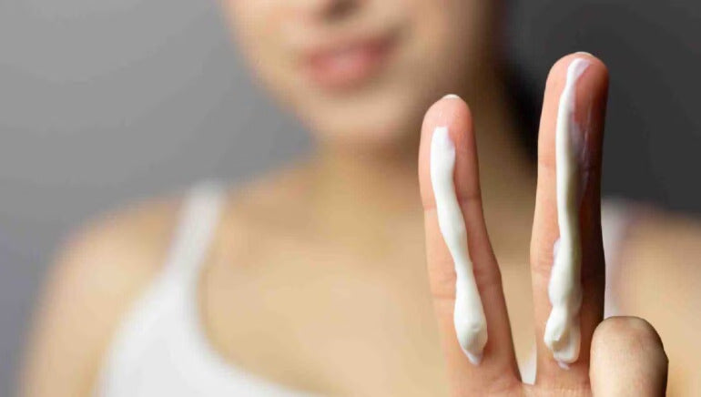 Woman showing 2 fingers covered by 2 lines of lotion