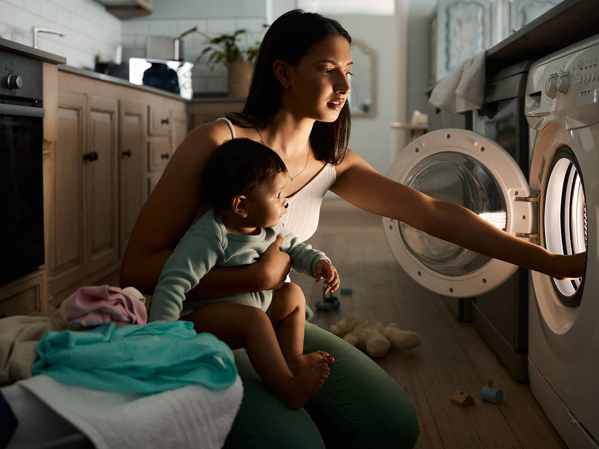 person with baby loading the washer machine