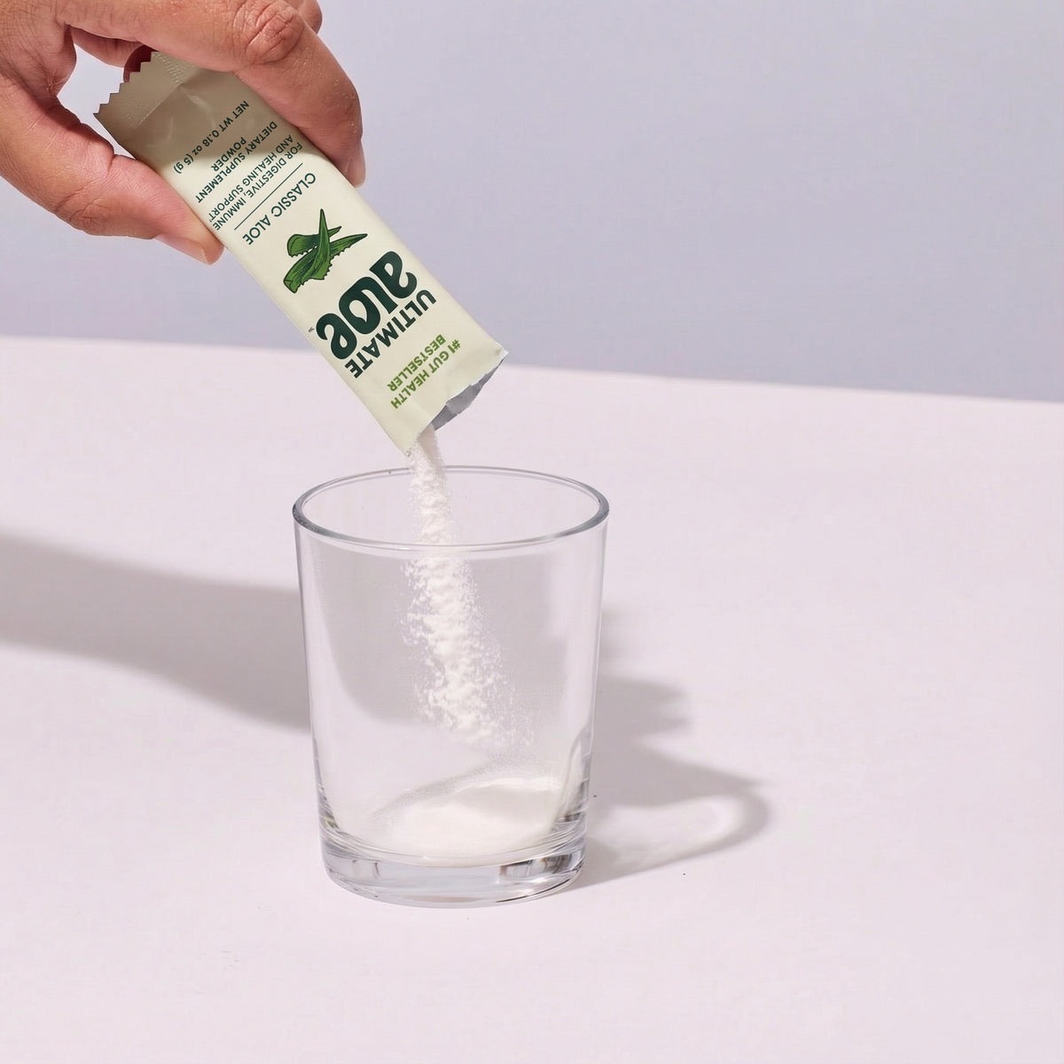 image of a person pouring Ultimate Aloe Powder into a cup.