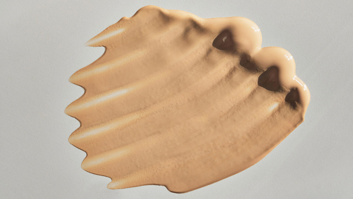 woman with a brush to her face and Motives Liquid Powder in her hand