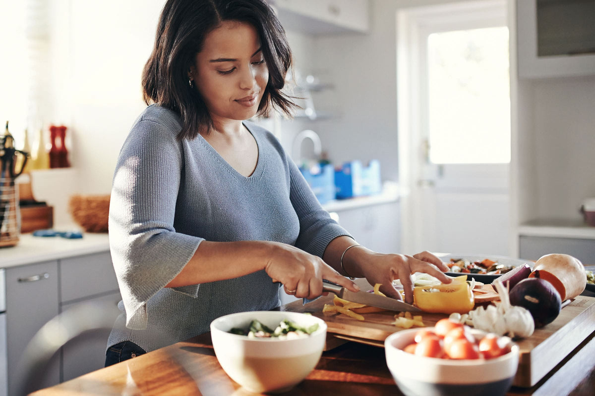 image of a woman chopping vegetables in the kitchen