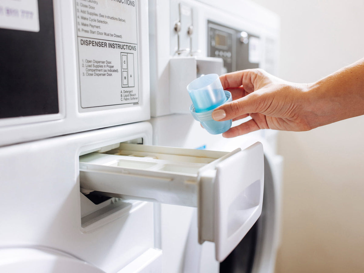 image of someone pouring laundry detergent into a washer machine