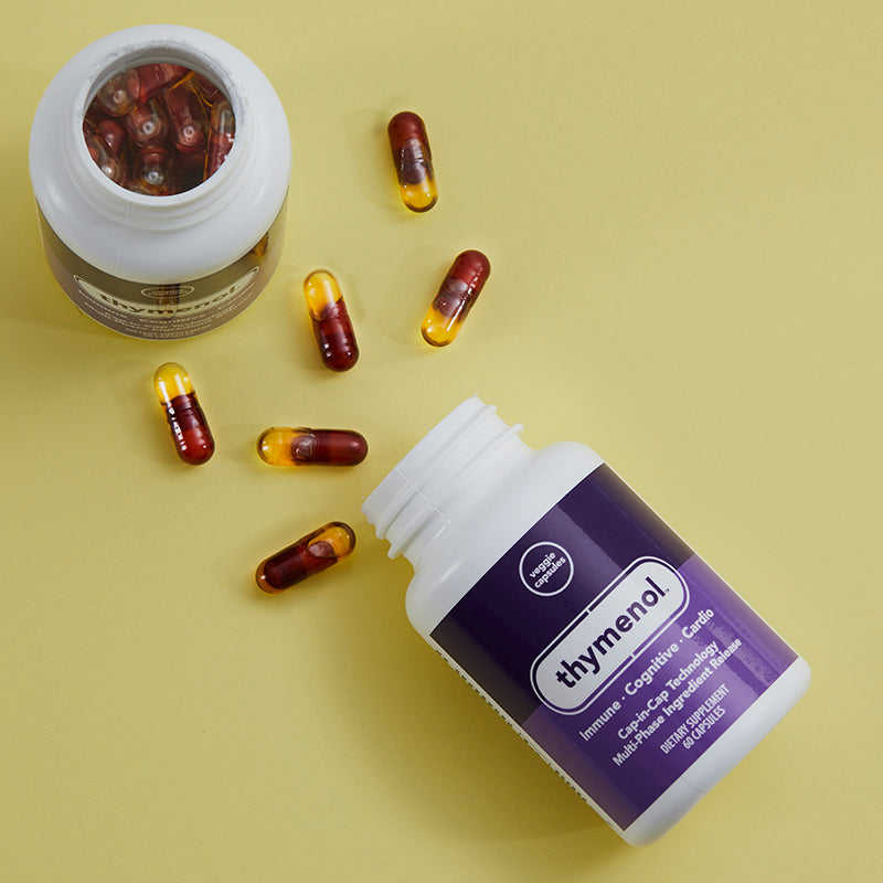 Open Thymenol bottles, with capsules lying beside them on a yellow table