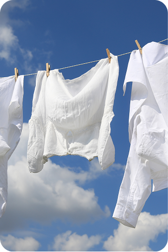 White clothing items hanging on a clothesline with wooden clips against a bright blue sky with clouds.