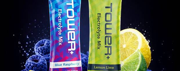 Two Tower+ electrolyte mix packets, one blue raspberry and one lemon lime, with fruit graphics on a dark background.