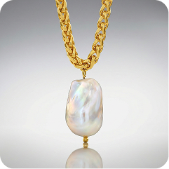 A gold chain necklace with a large, irregular baroque pearl pendant, shown against a neutral gray gradient background with a soft reflection below.
