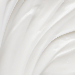 A close-up texture shot of a thick, creamy white cosmetic cream with soft, flowing ridges.