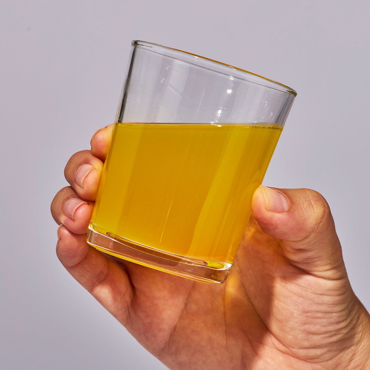 Image of someone's hand holding a glass containing one serving of Isotonix Multivitamin Fifty Plus.