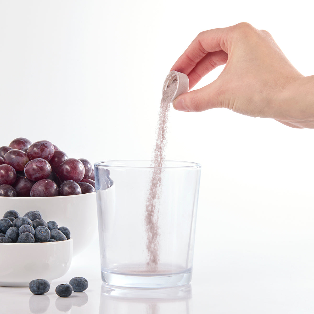 Image of person pouring one level cap of Isotonix powder into overcap