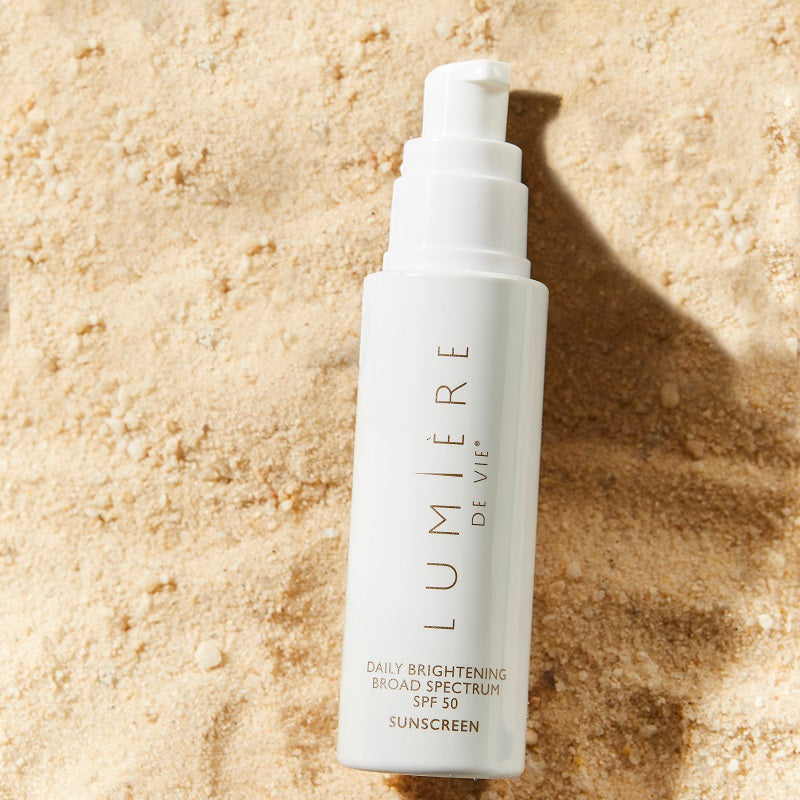 Lumière de Vie Daily Brightening Broad Spectrum SPF 50, laying in sand