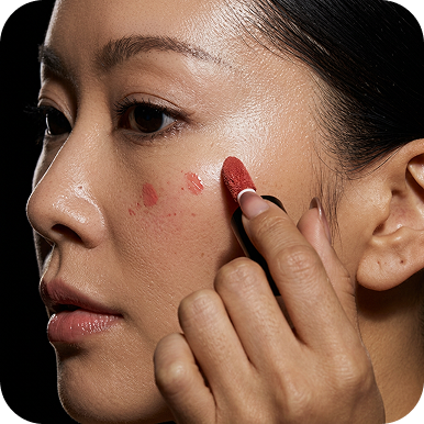 Close-up of a person applying makeup to their cheek.