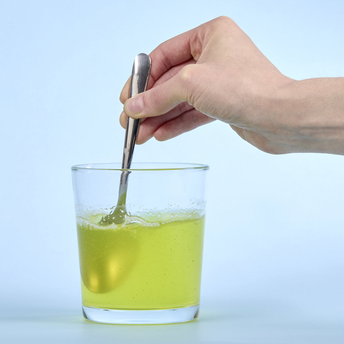 image of person mixing Isotonix Calcium in a clear glass with a spoon