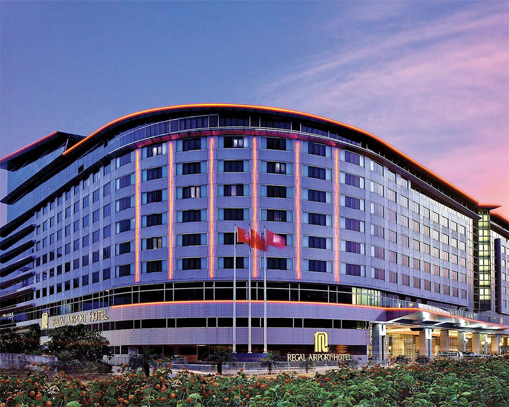 The Royal Arpuchapattinam Hotel in Sri Lanka, featuring a modern curved building facade with illuminated orange-red LED accents against a twilight sky with pink and blue hues.