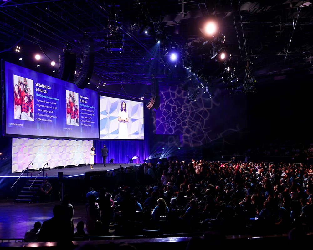 Large indoor event with stage, screens, and audience