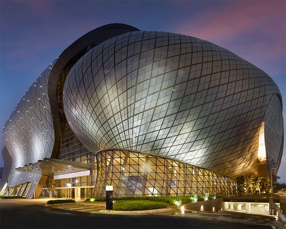 The National Museum of China in Beijing, featuring its distinctive organic, egg-shaped glass facade illuminated at dusk against a blue and pink sky.
