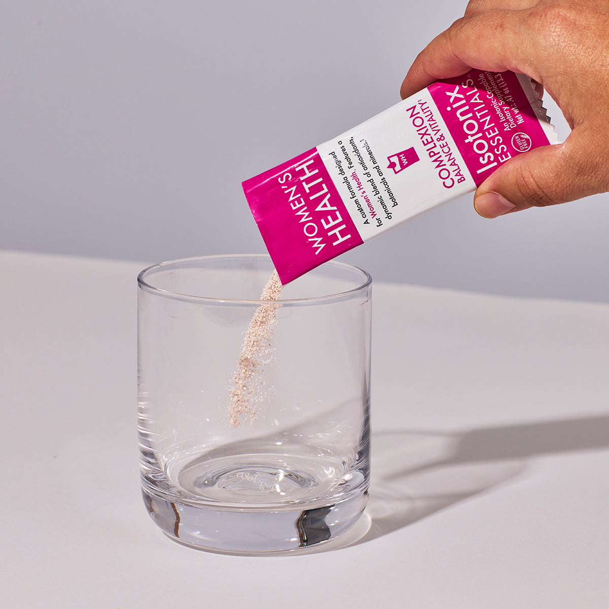 image of someone's hand pouring a packet of Isotonix Women's Health into a glass