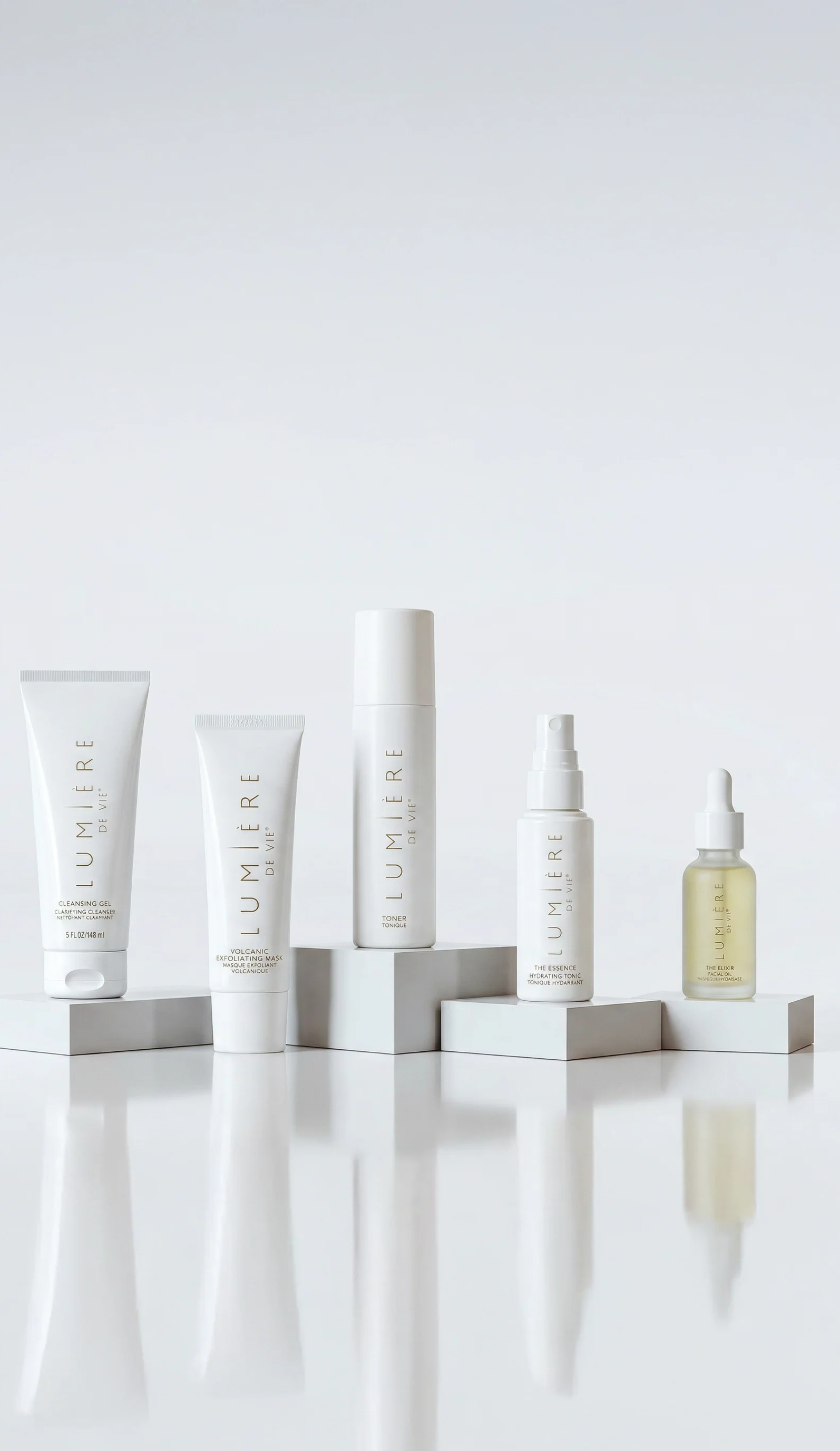 Five skincare products from the brand Lumiere arranged on white display blocks against a clean white background. The products include a squeeze tube, a small tube, a tall cylindrical bottle, a spray bottle, and a dropper bottle with pale yellow liquid.