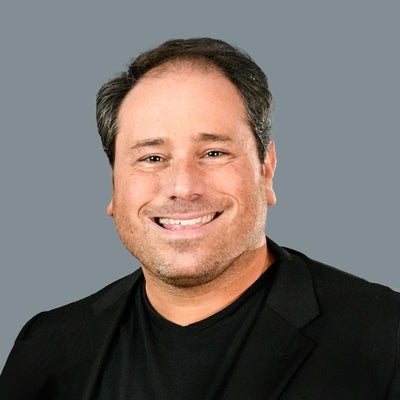 Man wearing a black jacket over a black shirt on a gray background