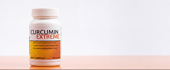 A white bottle of Curcumin Extreme dietary supplement standing on a pale peach surface against a white background.