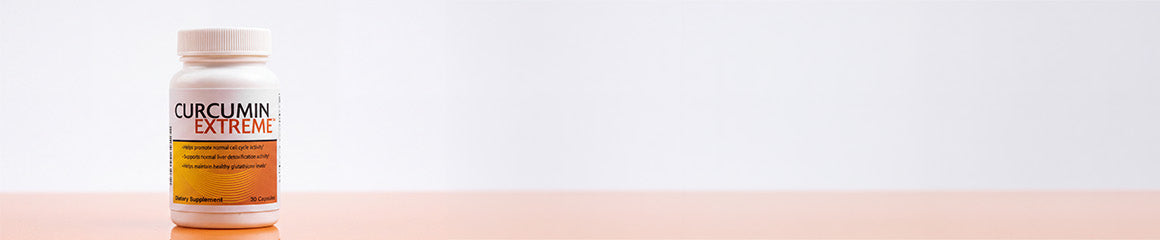 A white bottle of Curcumin Extreme dietary supplement standing on a pale peach surface against a white background.